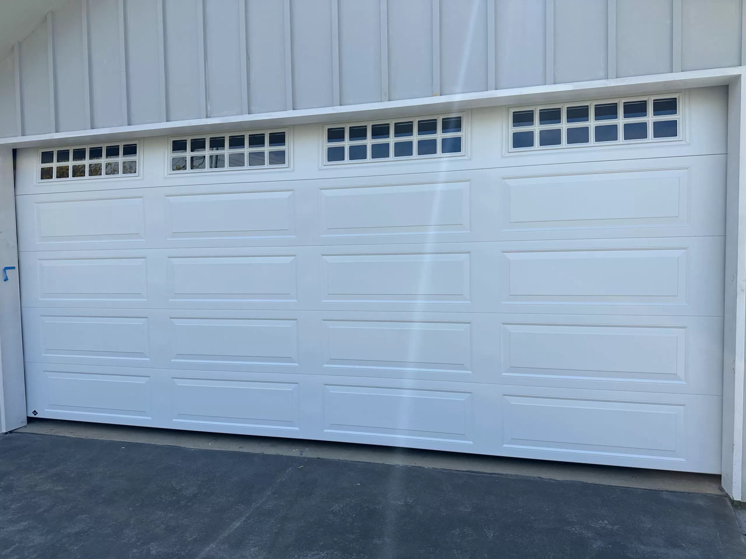 Newly installed white garage door in a brick-walled house with a tiled roof.