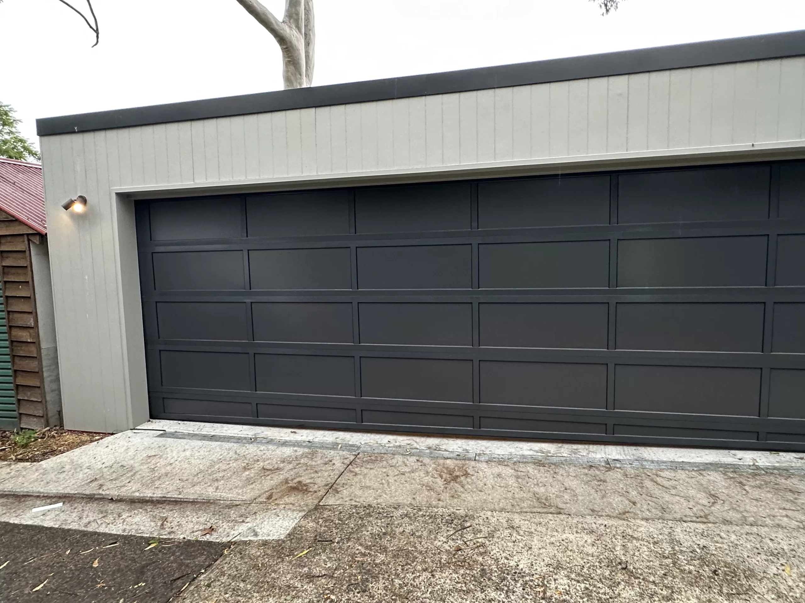 A sleek black sectional garage door installed on a modern garage.